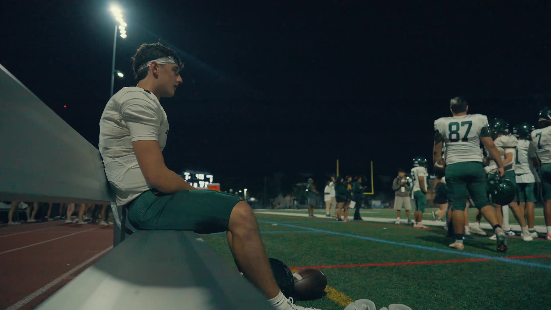 Lane Tech football player seated on the sideline under stadium lights, from the Episode 3 teaser