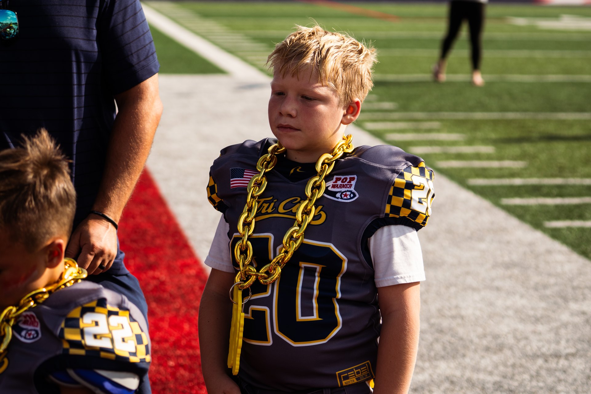 Tri-City football player wearing a gold chain on the sideline